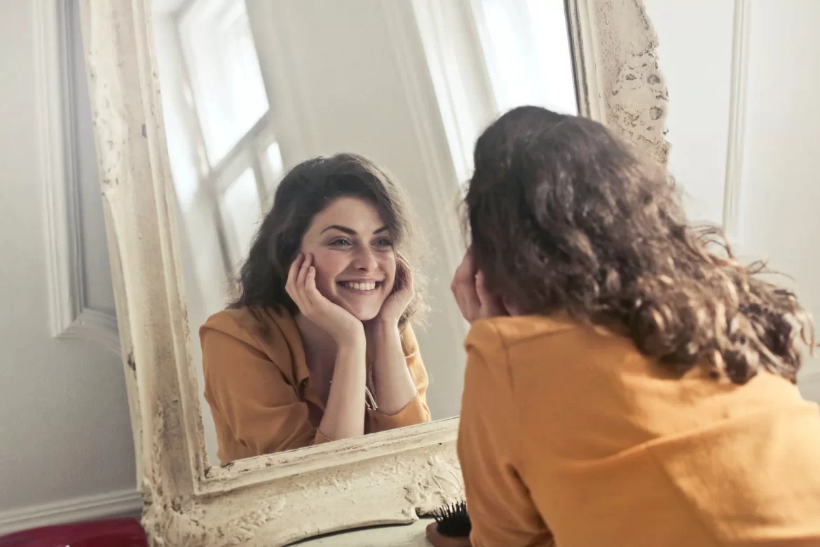 Beautiful women looking at herself in the mirror and smiling
