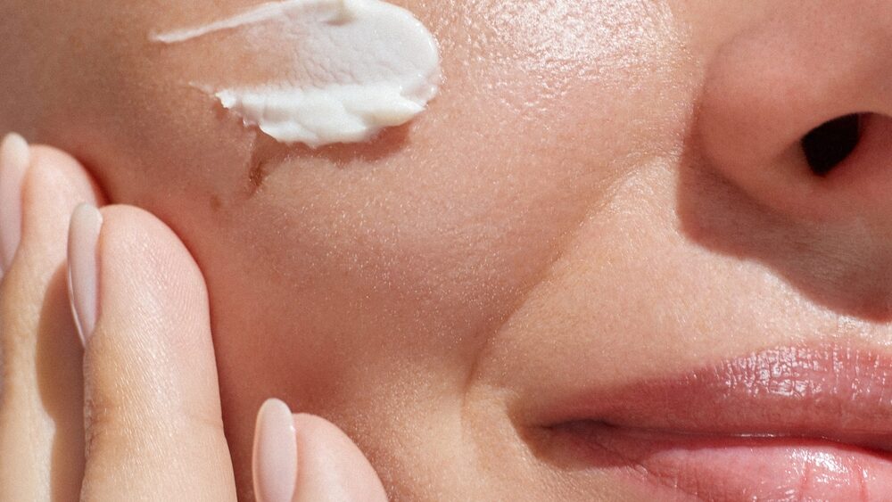 Close up of women face with cream on cheek representing Hydrating Cosmetics