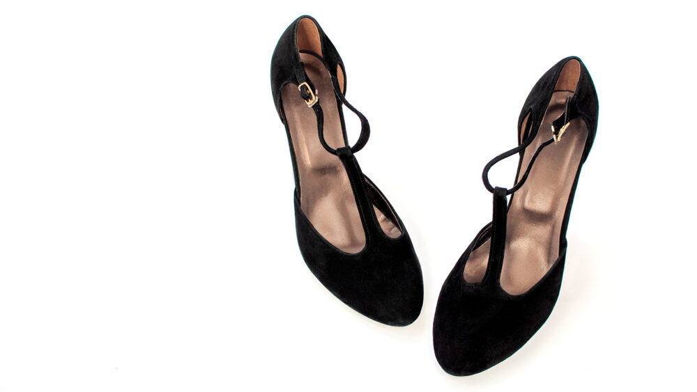 Women's black suede shoes with t-straps located toes to each other isolate on a white background