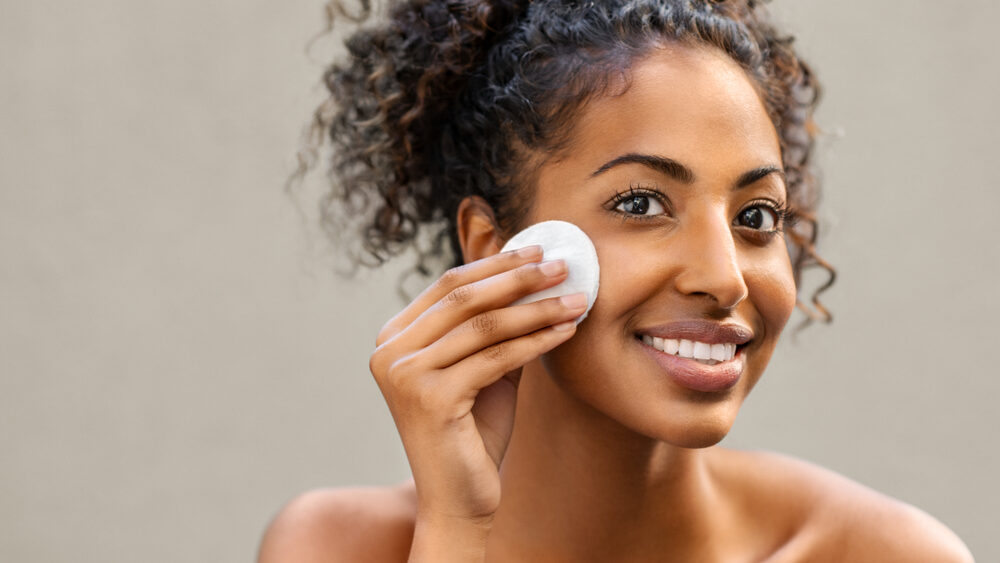 Beautiful woman cleaning her face with cotton pad