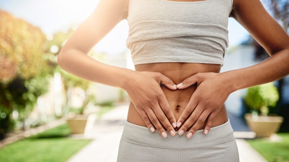 The connection between our intestinal and skin health represented by close up of women abdomen with her both hands in it